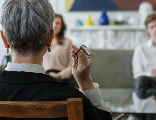 A therapist leads a couple's therapy session in a modern office setting.